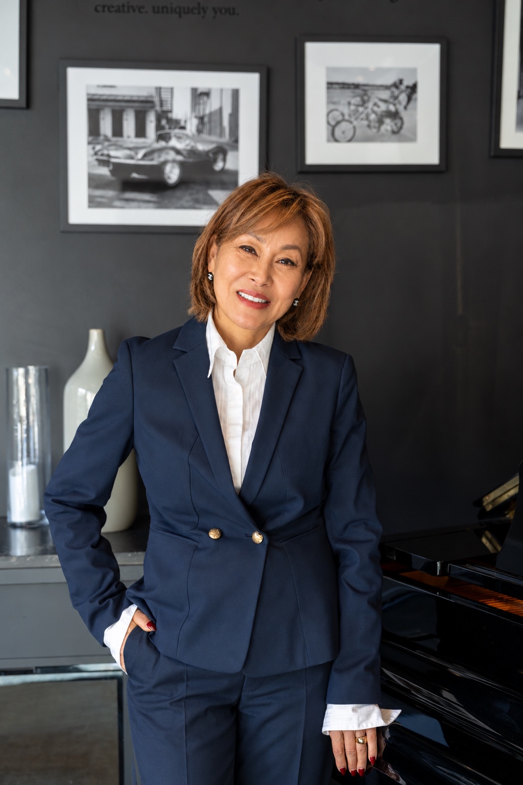 Kelly Hwang smiling in a navy suit with one hand in her pocket